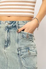 Minifalda de jean celeste con efecto lavado, corte recto y múltiples bolsillos cargo con solapa y botón.
