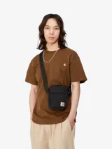 Bandolera Carhartt Jake de lona de poliéster reciclado repelente al agua, color negro, con compartimento principal con cremallera, bolsillo frontal y bolsillo interior de malla.