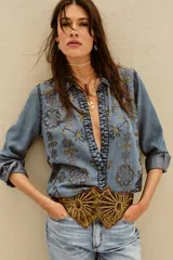 Camisa de tencel celeste con bordado de lentejuelas doradas, calce recto, manga larga y cuello camisero.