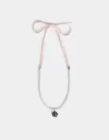 Collar corto de perlas sintéticas con dije de rosa metálica plateada y cierre de cinta de terciopelo negro.