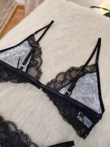 Conjunto de lencería compuesto por un corpiño triangular sin aro con estampado animal print y detalles de encaje negro, y una bombacha tipo colaless con el mismo estampado y borde de encaje negro. El corpiño tiene cierre frontal.