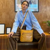 Bandolera marrón de cuero sintético con correa larga regulable combinada a tono. Tiene dos bolsillos frontales con cierre, apertura superior con cierre, división interna, bolsillos internos y bolsillo trasero con cierre.