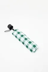 Paraguas plegable con funda protectora de tela estampada a cuadros vichy en tonos verde oscuro y blanco. Posee mango y remate de plástico negro.