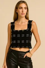 Top negro de cuero genuino con diseño de autor, compuesto por paneles rectangulares entrelazados con ganchos metálicos plateados. Posee escote cuadrado y tirantes anchos.