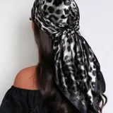 Pañuelo cuadrado de tela satinada con estampado animal print en tonos blanco y negro.
