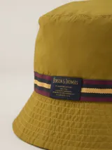 Gorro tipo bucket color mostaza con cinta decorativa a rayas horizontales en tonos bordó, amarillo y azul marino.