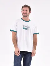 Remera blanca de manga corta con cuello redondo y ribete verde en cuello y mangas. Estampado frontal con texto "Court Classics" y diseño de pelotas de tenis.