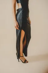 Vestido largo de fiesta negro brillante, de un solo hombro, con abertura lateral en la falda y corte ajustado al cuerpo.