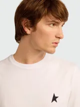 Remera de algodón color blanco roto con cuello redondo y un pequeño logo de estrella negra estampada en el pecho.