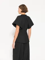 Blazer negro de lanita viscosa con cuello mao y mangas ranglan abullonadas tipo balloon con frunces en la unión con el cuello. Incluye pinza lateral que mejora el calce en la sisa, bolsillos ojal con tapa y cierre con broche bombé super black.