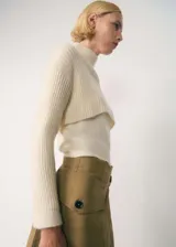 Sweater corto color crema de tejido de punto acanalado, con cuello alto y mangas largas.