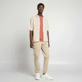Camisa de manga corta color beige claro, con cuello clásico y cierre frontal con botones. Confeccionada en mezcla de lino.