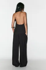 Top chaleco negro con cuello halter y cierre frontal con botones forrados.