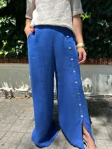 Pantalón de lino azul francia, de corte ancho y tiro alto, con bolsillos laterales y detalle de botones en el lateral de la pierna.