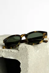 Lentes de sol con montura gruesa color carey y lentes oscuros.