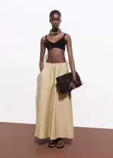 Falda larga color beige, de tiro bajo y corte evasé, con cintura elástica y bolsillos laterales.