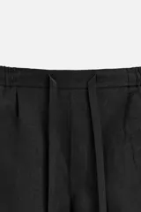 Bermuda regular fit negra confeccionada en tejido de lino. Cintura elástica ajustable con cordón y pliegues frontales. Bolsillos frontales y detalle de bolsillos traseros de plastrón.