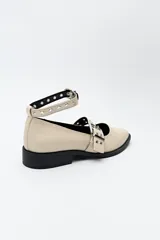 Zapato tipo zueco negro charol con punta fina, doble tira con hebillas metálicas y pulsera al tobillo con tachas.