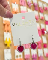 Aros colgantes con aro de acero plateado y dije circular color fucsia con borde de strass.