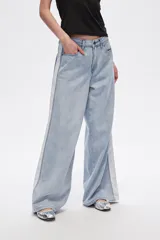 Pantalón de jean celeste de corte ancho con bolsillos y detalle de franja blanca en los laterales.