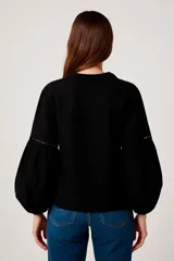 Blusa negra con escote en V con lazos, mangas largas abullonadas y puños elásticos.