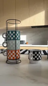 Set de 4 tazas de café en colores variados con diseño a cuadros y agarre en acero negro.