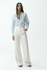 Camisa celeste con rayas verticales en blanco y amarillo, de corte entallado, cuello solapa y manga larga.