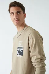 Remera de manga larga blanca con cuello redondo y estampado frontal con imagen de un pianista y texto en color celeste.