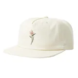 Gorro de visera chata color beige con bordado de flor en la parte frontal.