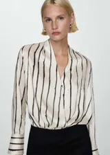 Blusa de poliéster color blanco con estampado de rayas verticales negras, escote cruzado en V y mangas largas con puños abotonados.
