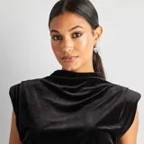 Camiseta sin mangas de terciopelo negro con cuello alto y hombreras marcadas.