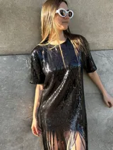 Vestido corto negro con lentejuelas, mangas cortas y flecos en el ruedo.