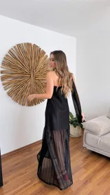 Vestido largo negro de tejido de punto con escote recto y breteles finos. La falda es de encaje transparente. Incluye una bufanda fina al tono.