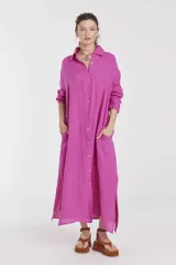 Vestido camisero largo color fucsia, de lino, con cuello camisero, mangas largas, cierre frontal con botones, bolsillos laterales y aberturas laterales en el ruedo.