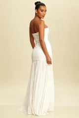 Vestido largo de fiesta blanco, estilo strapless, con corte ajustado en la parte superior y falda larga con caída fluida.