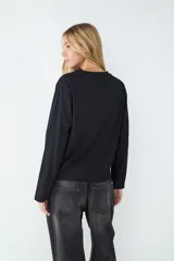 Jean de tiro alto color negro, corte loose con pernera ancha. Diseño clásico de cinco bolsillos con cierre de cremallera y botón metálico.