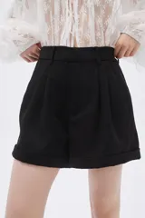 Short negro de vestir con pinzas, tiro alto y ruedo con dobladillo.