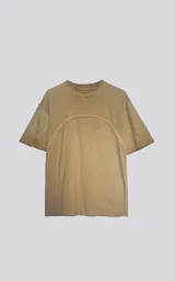 Remera oversize de algodón, color mostaza con efecto batik artesanal. Presenta costuras decorativas arqueadas que unen el cuello con los hombros y el torso.