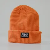 Gorro de lana acrílica color naranja, estilo beanie con etiqueta negra con el logo de la marca Pulau.