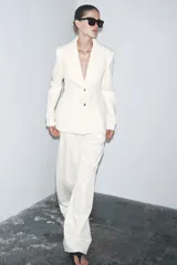 Blazer color blanco confeccionado en algodón, con cuello solapa de muescas y manga larga. Tiene bolsillos con solapa en delantero, forro interior a tono y cierre frontal con botones metálicos en relieve.
