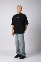 Remera negra de corte oversize con cuello redondo y mangas cortas. Estampado pequeño en el frente y parche estampado en la espalda.