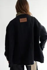 Campera de jean azul con corte oversize, cuello de pana color borgoña, cierre con botones metálicos y cinturón de lazo.