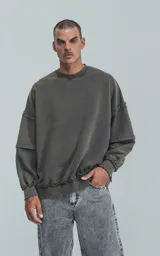 Buzo cuello redondo color gris oscuro con efecto gastado, costuras expuestas, calce oversize y roturas.