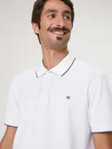 Camisa polo color rosa claro con cuello clásico, tapeta de dos botones y bordado de logo en el pecho. Presenta ribete azul marino en cuello y mangas. Corte clásico.