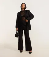 Pantalón de viscosa con corte flare, cintura alta, sin estampa, con frisos delanteros y abertura lateral en el bajo.