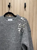 Buzo de punto color gris con escote redondo, corte clásico y detalle bordado de lentejuelas plateadas en el hombro.