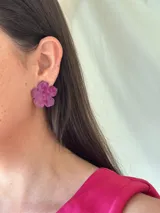Aros con forma de flor color fucsia con brillos.
