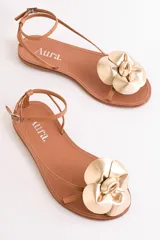 Sandalias bajas color cuero con tiras finas y aplique de flor dorada.