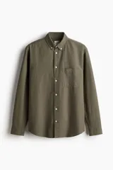 Camisa de algodón Oxford color verde oliva, de corte estándar, con cuello abotonado, tapeta clásica, bolsillo superior abierto, manga larga con puños abotonados y bajo levemente redondeado.