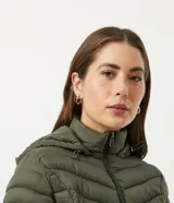 Campera puffer larga color verde militar, confeccionada en poliamida con relleno de poliéster. Tiene capucha ajustable, cierre frontal con cremallera, cuello alto y bolsillos laterales.